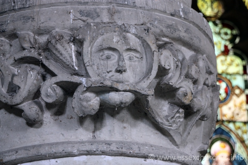 St John the Baptist, Mucking Church – Circular pier in the S aisle arcade, with stiff-leaf capital. Two faces appear - one facing north, the other south-west. This one - north facing, is a green man.