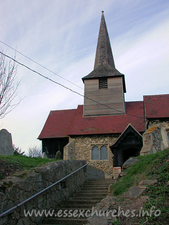 St Nicholas, Laindon Church – This view up to the church shows the timber belfry, with its dark weather-boarding, and its broach spire.